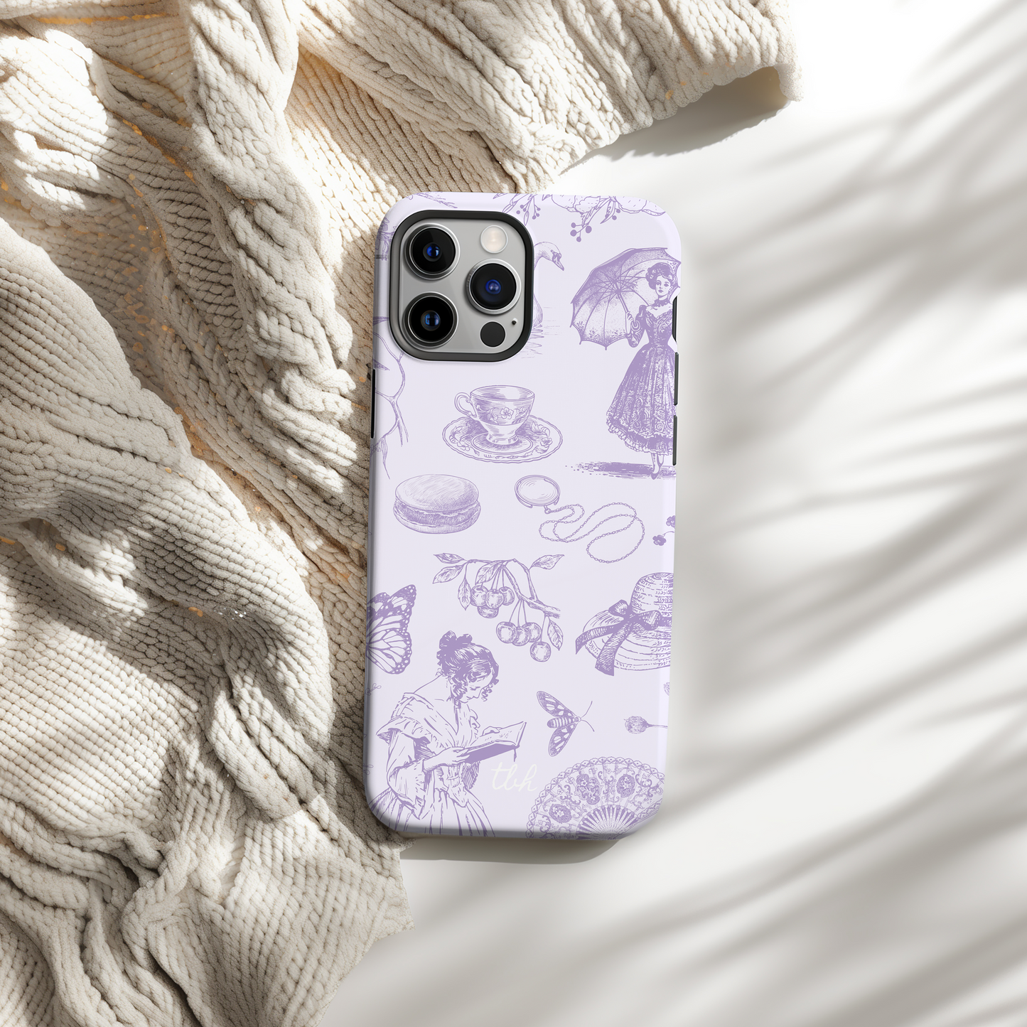 Phone case with purple illustrations on a textured beige surface