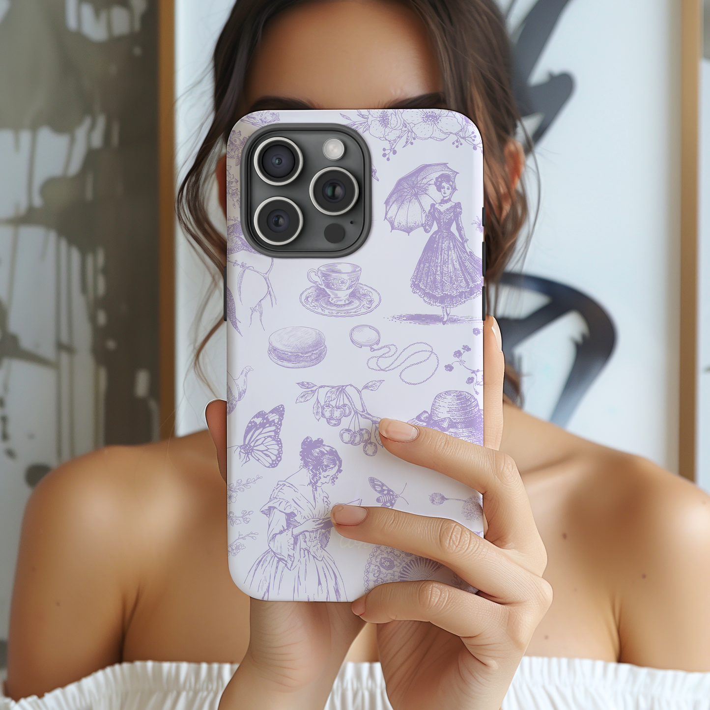 Person holding a phone with a decorative case featuring illustrations on a blurred background