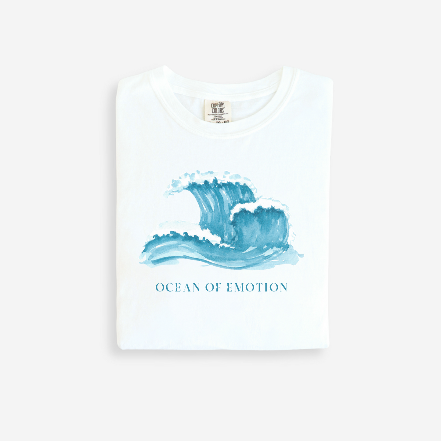 White t-shirt with blue wave design and 'Ocean of Emotion' text on a white background